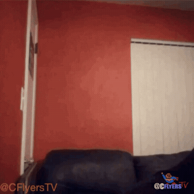 Black Couch With Red Wall And Flyers TV Logo GIF
