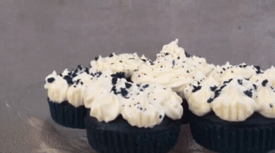 Black Cupcakes With White Frosting And Black Sprinkles On Top GIF