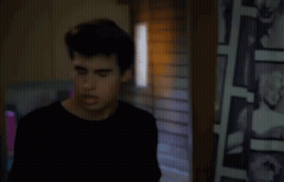 Black-Haired Woman Sitting In Front Of Bookshelf GIF