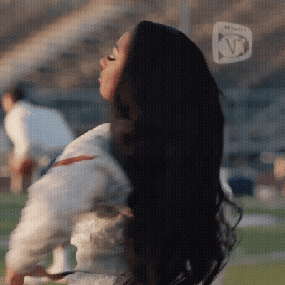 Black-Haired Woman Standing On Football Field KT Logo GIF