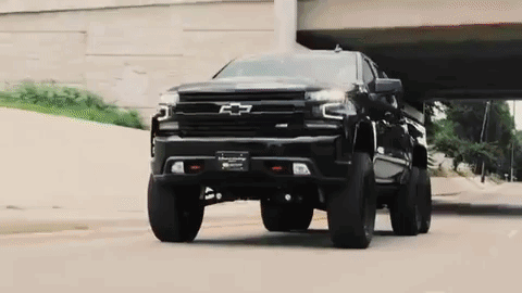 Black Truck Driving Under Bridge On City Street GIF