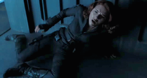 Black Widow Is Laying On The Floor In A Dark Room With A Gun In Her Hand . GIF
