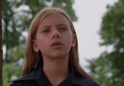 Blonde Girl In Blue Shirt Looking At Camera GIF