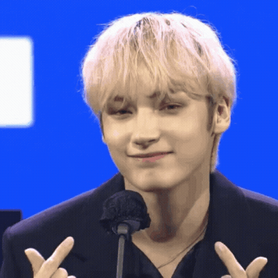 Blonde Man Giving Peace Sign At Microphone GIF
