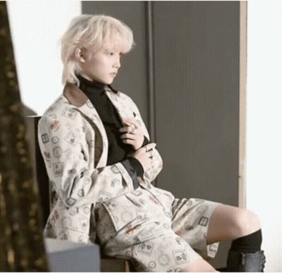 Blonde Man In Suit With Stamps Sitting On Chair GIF