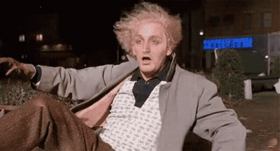Blonde Man Laying In Front Of Building With Set Cards Sign GIF