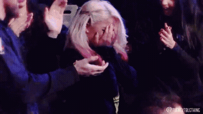 Blonde Woman Covering Face as Crowd Applauds