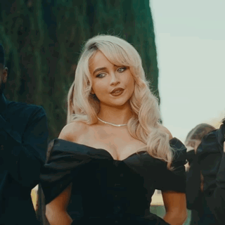 Blonde Woman In Black Dress Standing In Front Of Man GIF