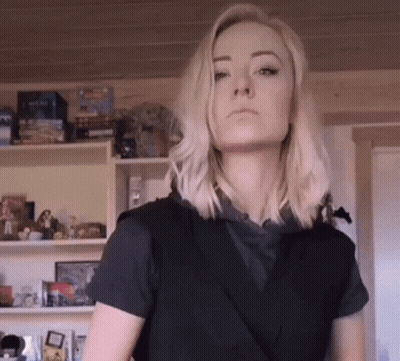 Blonde Woman In Black Shirt In Front Of Toy Shelf GIF