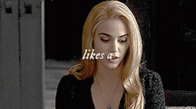 Blonde Woman In Black Shirt With Necklace Saying Likes A GIF