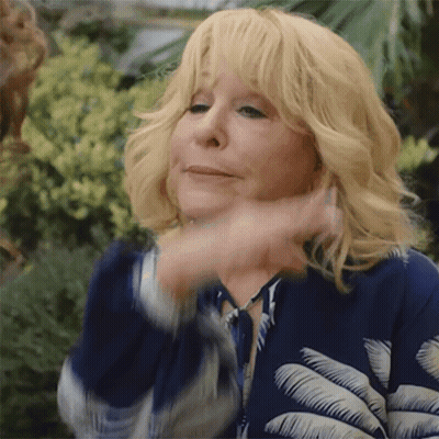 Blonde Woman In Blue Jacket With Palm Leaves Making Funny Face GIF