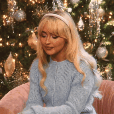 Blonde Woman In Headband And Blue Sweater By Christmas Tree GIF