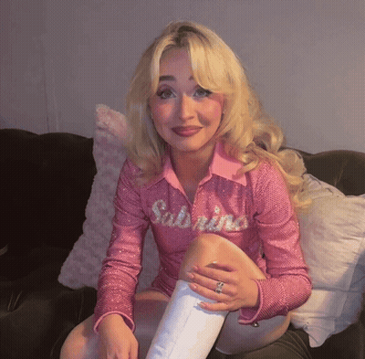 Blonde Woman In Pink Sabrina Shirt On Couch GIF