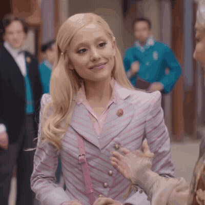 Blonde Woman In Striped Jacket And Pink Purse Smiling GIF