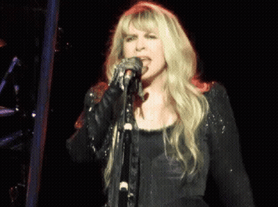 Blonde Woman Singing Into Microphone On Stage GIF