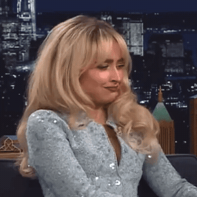 Blonde Woman Sitting On Couch Before City Skyline GIF