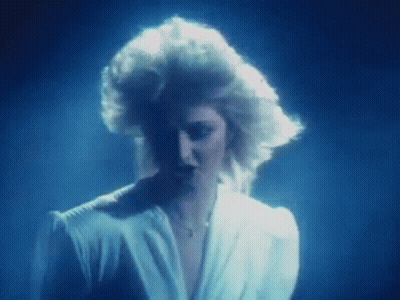 Blonde Woman Standing In Dark Room With Blue Light GIF