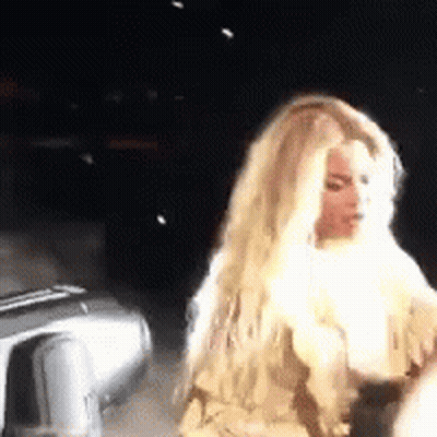 Blonde Woman Standing Next To Car In Dark GIF