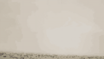 Blue And Red Robot Flying Through Cloudy Sky GIF