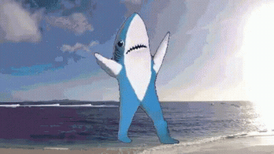 Blue and White Shark Standing on Beach With Arms Outstretched