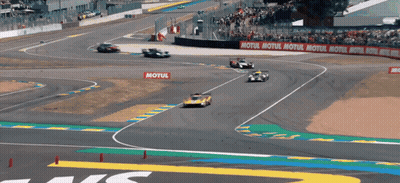 Blue Car Driving Down Street Past Crowd GIF