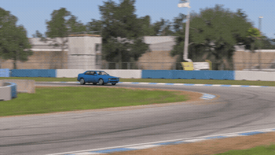 Blue Car Driving On Race Track With Blue And White Fence GIF