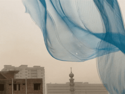 Blue Cloth Blowing in Wind in Front of Brick Building