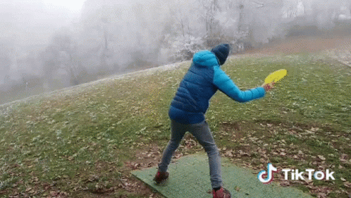 Blue Jacket Man Throwing Frisbee Green Mat TikTok Watermark GIF
