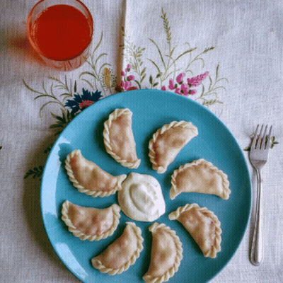 Blue Plate With Dumplings And Sour Cream Next To Orange Juice GIF