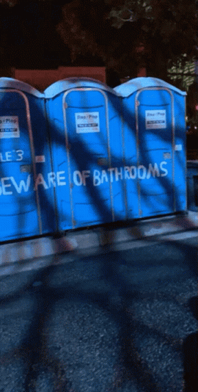 Blue Portable Toilets With Beware Of Bathrooms Written On Them GIF