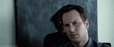 Blue Shirt Man Sitting In Front Of Demon Painting GIF