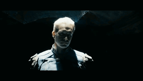 Blue-Suited Man Looking At Camera In Dark Room GIF