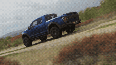 Blue Truck Driving On Dirt Road With Mountains GIF