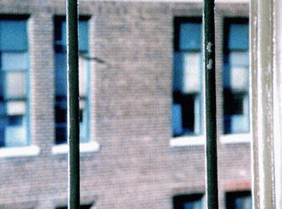 Blurry Brick Building With Blue Windows And Green Pole GIF