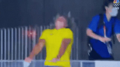Blurry Man In Yellow Shirt Next To Fence GIF