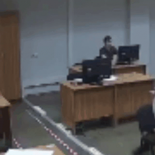 Blurry Man Standing At Desk With Computer GIF
