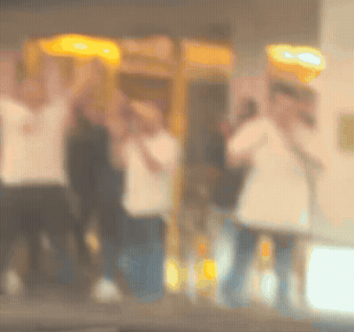 Blurry People Standing In Front Of Payphone GIF