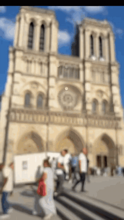 Blurry People Walking By Tall Building GIF