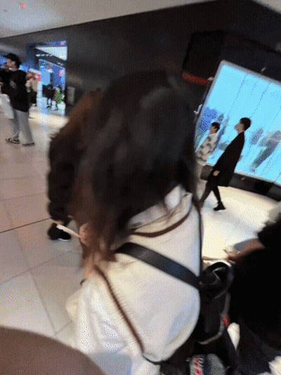 Blurry People Walking In Hallway With Red Exit Sign GIF
