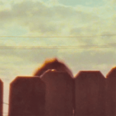 Blurry Person Behind Fence With Cloudy Sky GIF