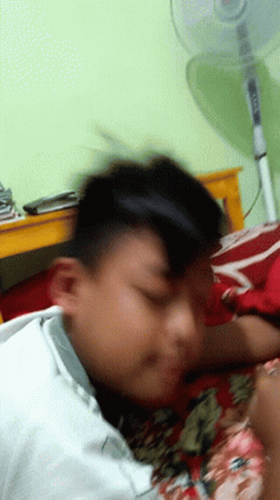 Blurry Person Laying On Bed With Fan GIF