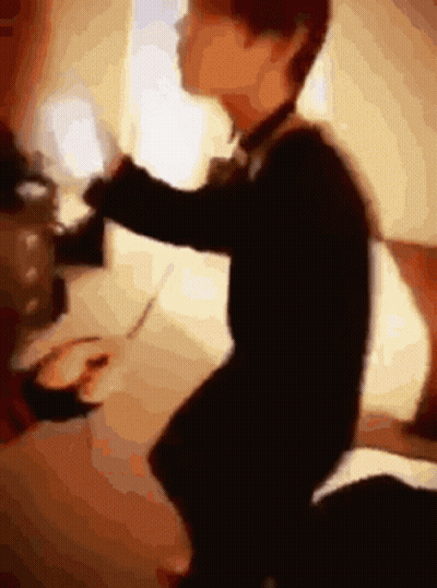 Blurry Person Sitting On Bed With Remote GIF