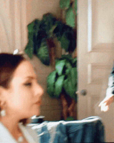 Blurry Woman At Door With Plant GIF