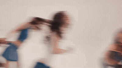 Blurry Woman Walking In Front Of White Wall GIF
