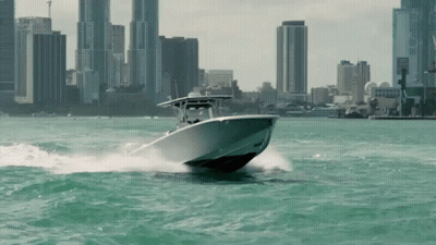 Boat Speeding Through Water With City Background GIF
