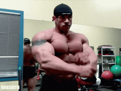 Bodybuilder Flexing Muscles In Front Of Muscul Sign GIF
