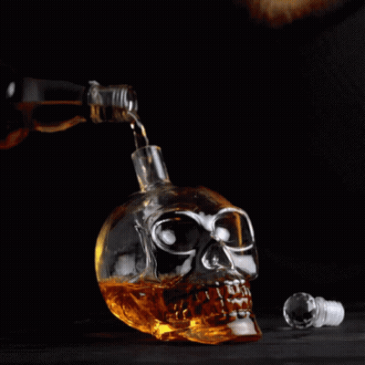 Bottle Pouring Alcohol Into Skull-Shaped Glass GIF