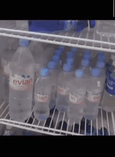 Bottles Of Evian Water Are Lined Up On A Shelf GIF