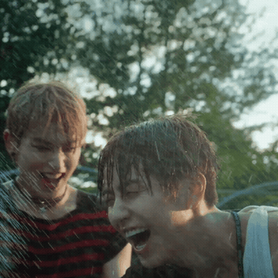 Boy And Girl Laughing Under Sprinkler GIF