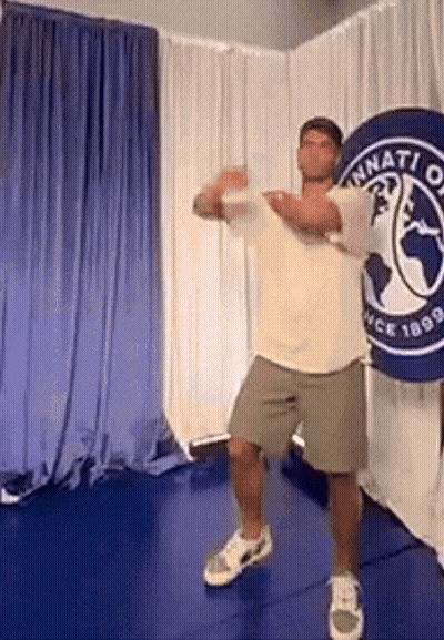 Boy And Girl Standing In Front Of Green And White Crown Logo GIF